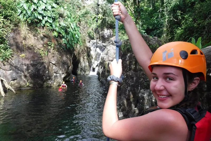 Guest swinging out on the rope swing over a waterfall pool in El Yunque