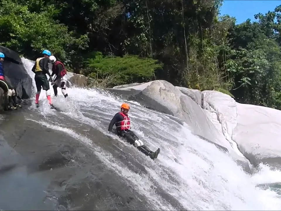Guest riding the long natural rock slide into a pool in the El Yunque canyon