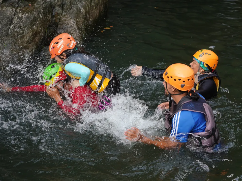 Guests in life jackets floating a whirlpool pool between boulders in El Yunque
