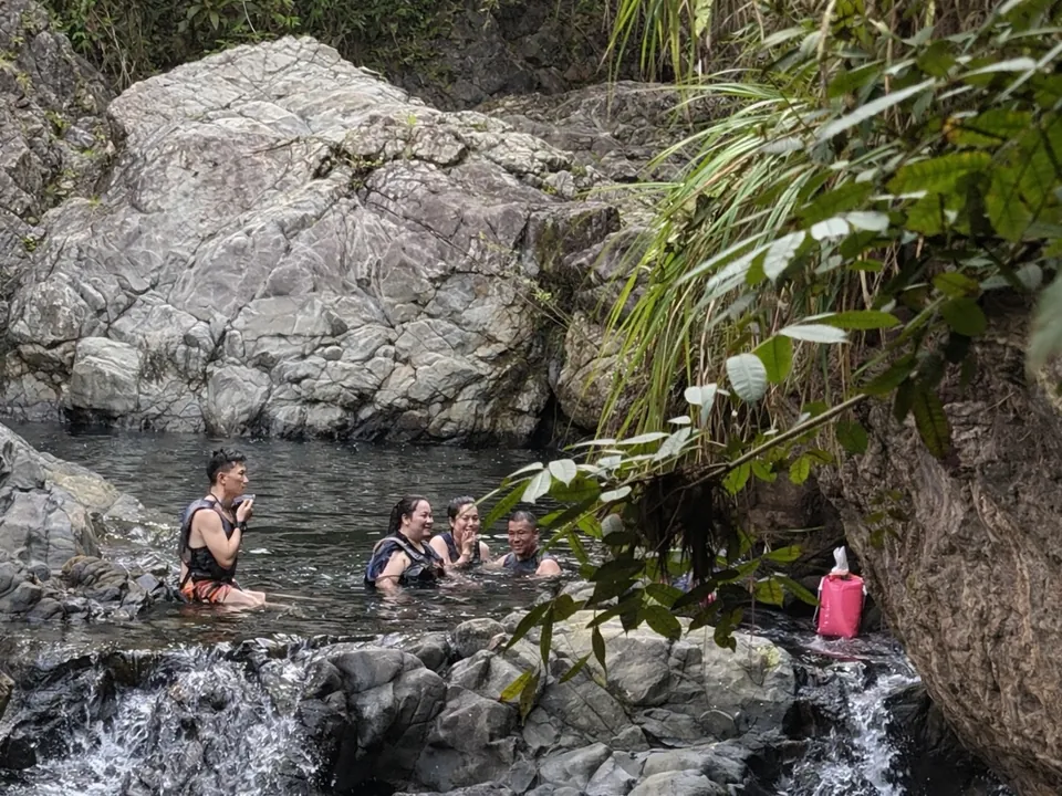Group in helmets and life jackets swimming in a waterfall pool on the south side of El Yunque