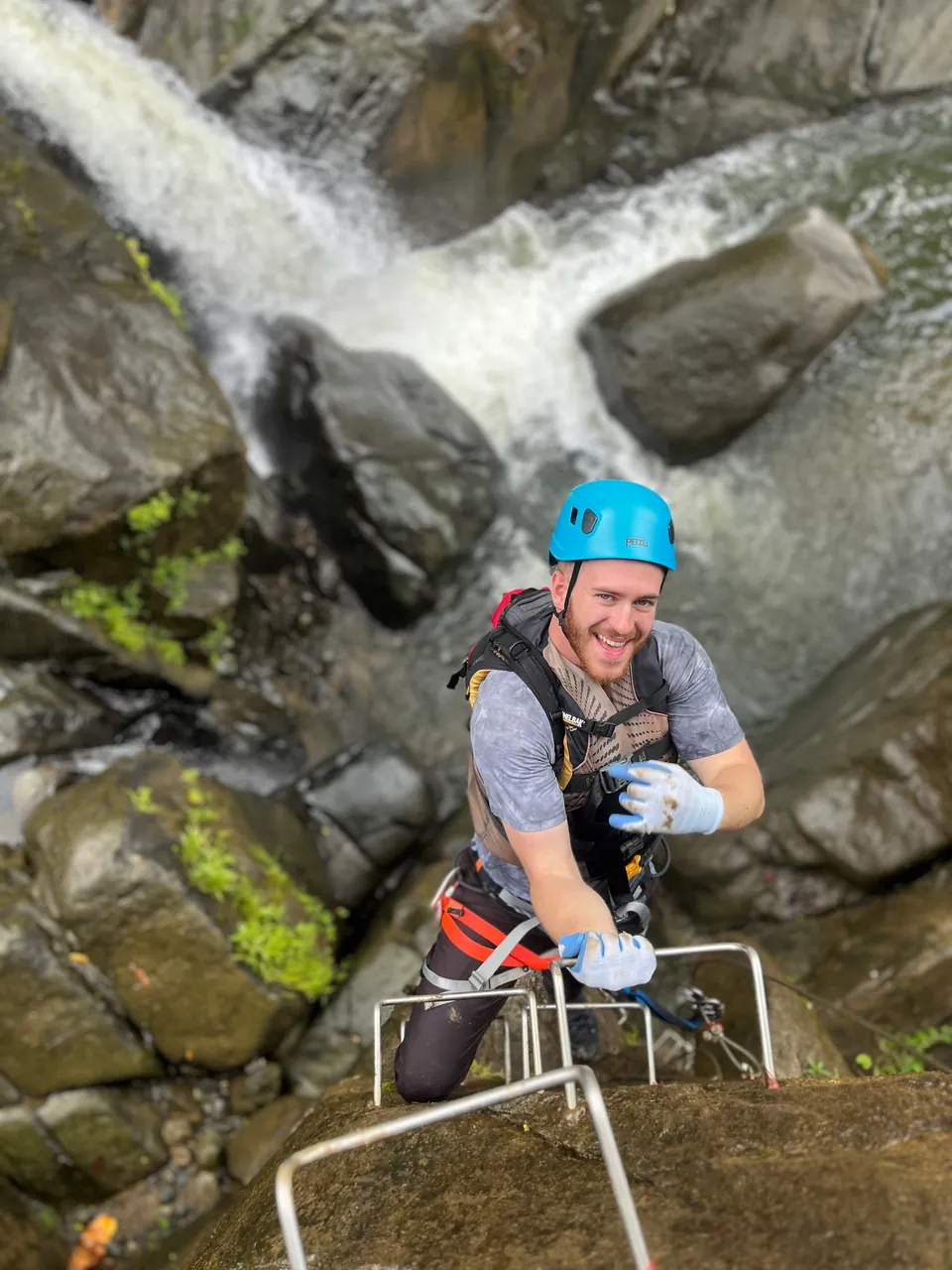 Climber on a fixed ladder beside the cascade on the El Yunque via ferrata