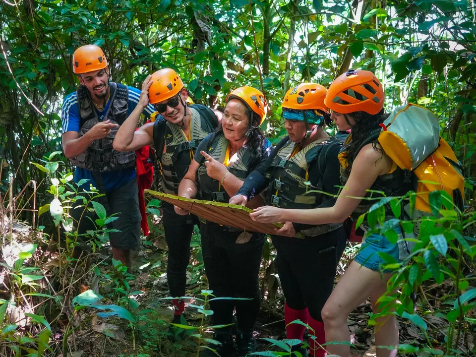 Small group in helmets walking the forest footpath toward the river in El Yunque